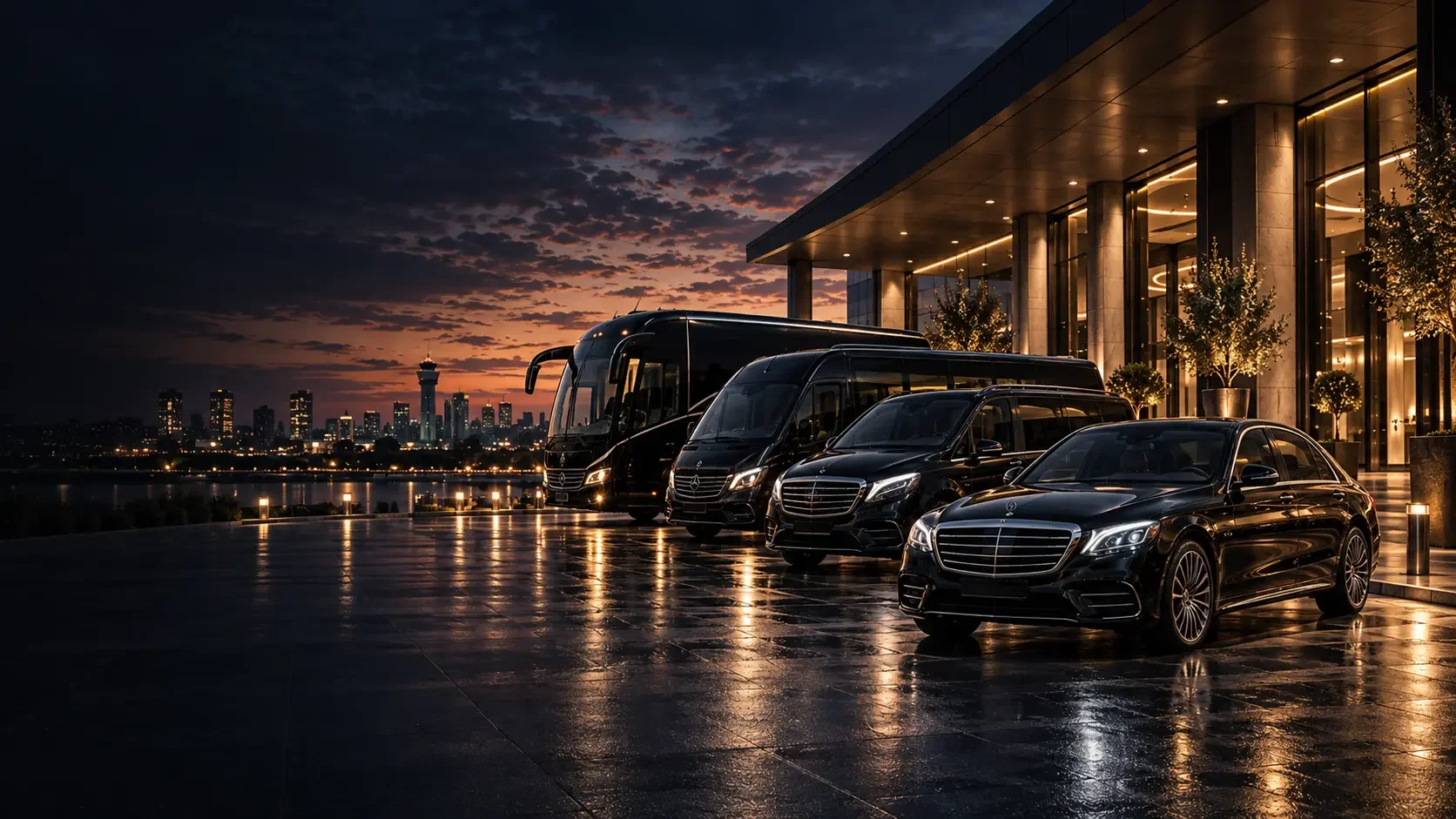 Representative scene: a black saloon, MPV, minibus and coach beside a warmly lit entrance at dusk.
